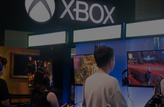 Young fairgoers playing Xbox games at a booth during Gamescom 2025 at the Cologne Trade Fair Center in Germany